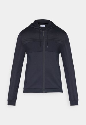 Marineblauwe hoodie met rits, voorzien van een getextureerd bovenpaneel, trekkoordkap, zijkstrepen en geribde manchetten. Gemaakt van een lichtgewicht, flexibel materiaal.