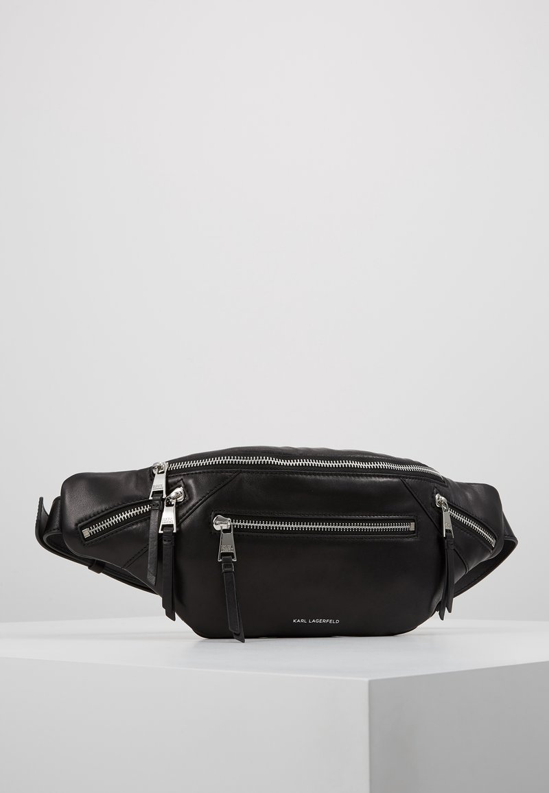 Marsupio in pelle nera con cerniere argento, due tasche frontali e dettaglio del logo; texture elegante e liscia, con tracolla regolabile.