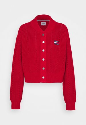 Cardigan rouge en maille avec manches longues, boutons-pression argentés sur le devant, poignets et ourlet côtelés, et petit logo Tommy Jeans sur la poitrine.