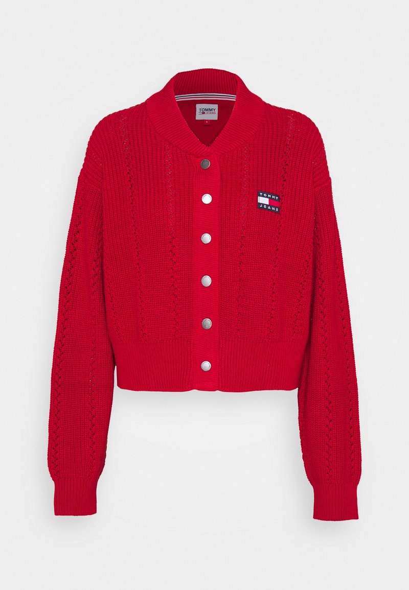 Cardigan rouge en maille avec manches longues, boutons-pression argentés sur le devant, poignets et ourlet côtelés, et petit logo Tommy Jeans sur la poitrine.