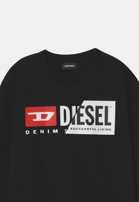 Černá mikina s pružným výstřihem, která má velké grafické logo v červené a bílé barvě s nápisem "DIESEL" a "DENIM SUCCESSFUL LIVING."