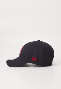 Gorra de béisbol azul marino con visera curvada, que presenta un logo rojo bordado y acentos. Hecha de tela con un diseño estructurado clásico.