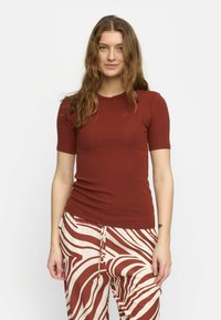 Geribbelde, korte mouw top in diep rood, gecombineerd met crèmekleurige broek met opvallende bruine strepen. Glad textuur met een getailleerd ontwerp.