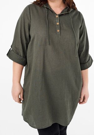 Camisa con capucha en tela de color verde oscuro con acabado texturizado. Cuenta con tres botones de madera y mangas que se pueden enrollar. Corte relajado, largo hasta la mitad del muslo.