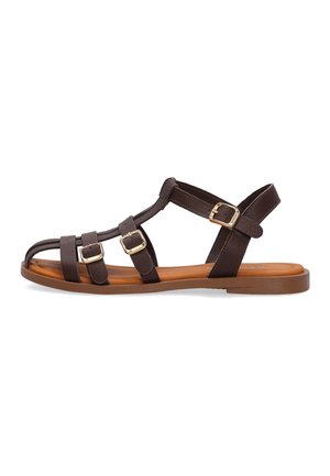Hnědý plochý sandal s několika pásky a třemi zlatými přezkami, otevřenou špičkou a opálenou polstrovanou podrážkou na bílém pozadí.