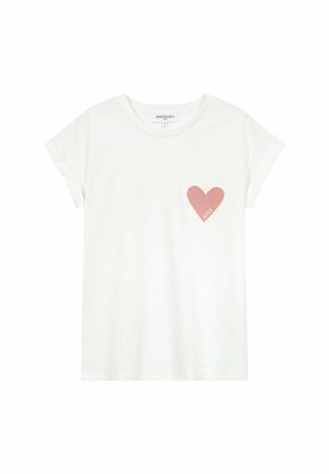 T-shirt en coton blanc à manches retroussées, arborant un motif de cœur rose sur la poitrine gauche avec le texte "KISS". Coupe décontractée, texture lisse.