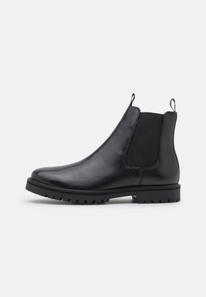 Schwarze Leder Chelsea-Boots mit elastischen Seitenpaneelen und Laschen, ausgestattet mit einer robusten schwarzen Gummisohle und glatter Oberfläche.