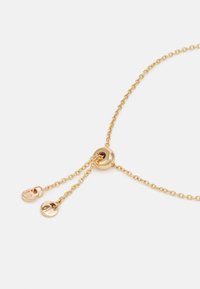 Collar de cadena de oro con una perla redonda y dos extremos ajustables, cada uno finalizando en un encantador circular liso. Textura suave y acabado brillante.