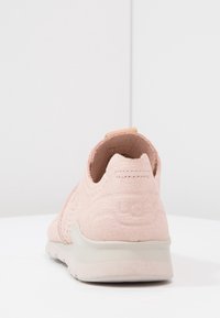 Světle růžové tenisky s texturovaným textilem na svršku, perforacemi pro prodyšnost, tvarovanou patou a bílou gumovou podrážkou.