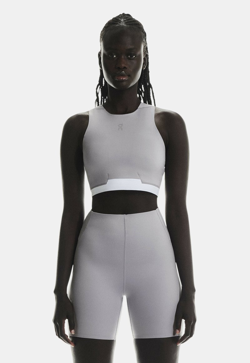 Soutien-gorge de sport gris clair et shorts taille haute en tissu lisse et extensible. Design minimaliste avec un accent réfléchissant sur le soutien-gorge.