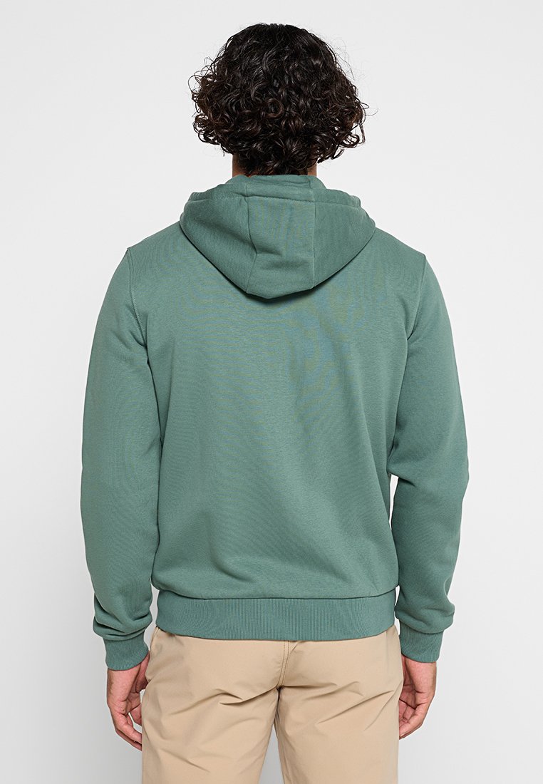 Zielona bluza z kapturem wykonana z miękkiego materiału, z kieszenią typu kangur i ściągaczami przy rękawach. Projekt jest klasyczny i casualowy.