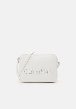 Witte rechthoekige schoudertas met verstelbare band en "Calvin Klein"-logo gevormd door kleine perforaties aan de voorkant.