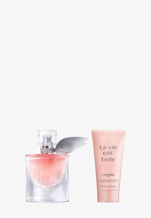 Botella cuadrada de cristal con perfume de líquido rosa y lazo plateado, junto a un tubo rosa de loción corporal de la fragancia La Vie Est Belle de Lancôme.