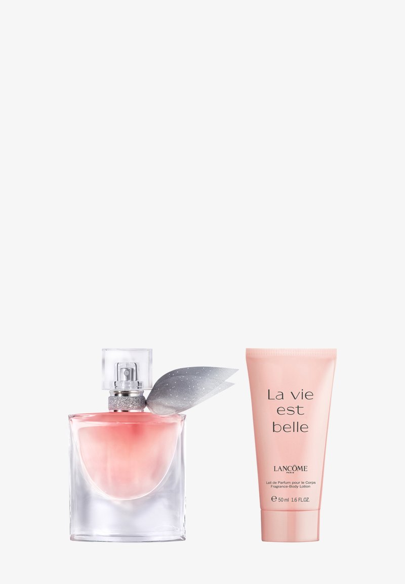 Flacon de parfum carré en verre avec un liquide rose et un nœud argenté, à côté d'un tube rose de lotion pour le corps parfumée La Vie Est Belle de Lancôme.