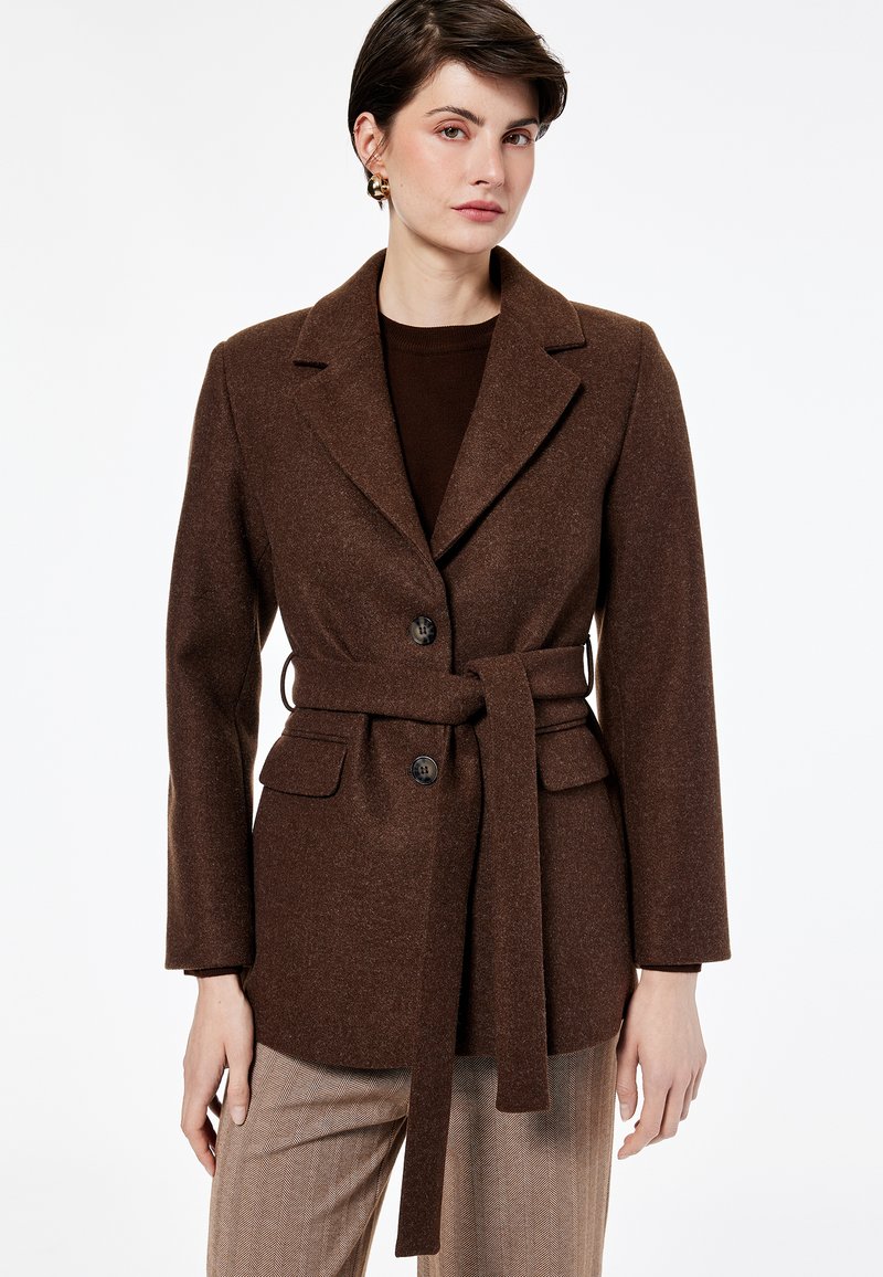 Blazer marrón de mezcla de lana con cintura ceñida con cinturón, solapas con muesca y dos bolsillos frontales. Presenta botones negros y un acabado texturizado.