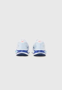 Light blue athletic shoes with a textured upper, featuring a dark blue sole and red accents. Both shoes are viewed from the back.