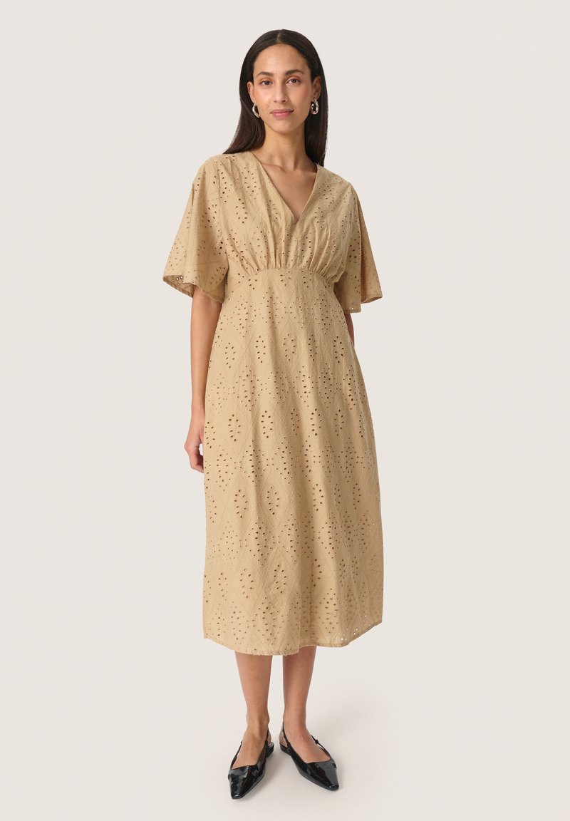 Beige bomull midi klänning med V-ringning, korta volangärmar och diamanthål. Bärs med svarta spetsiga ballerinas.