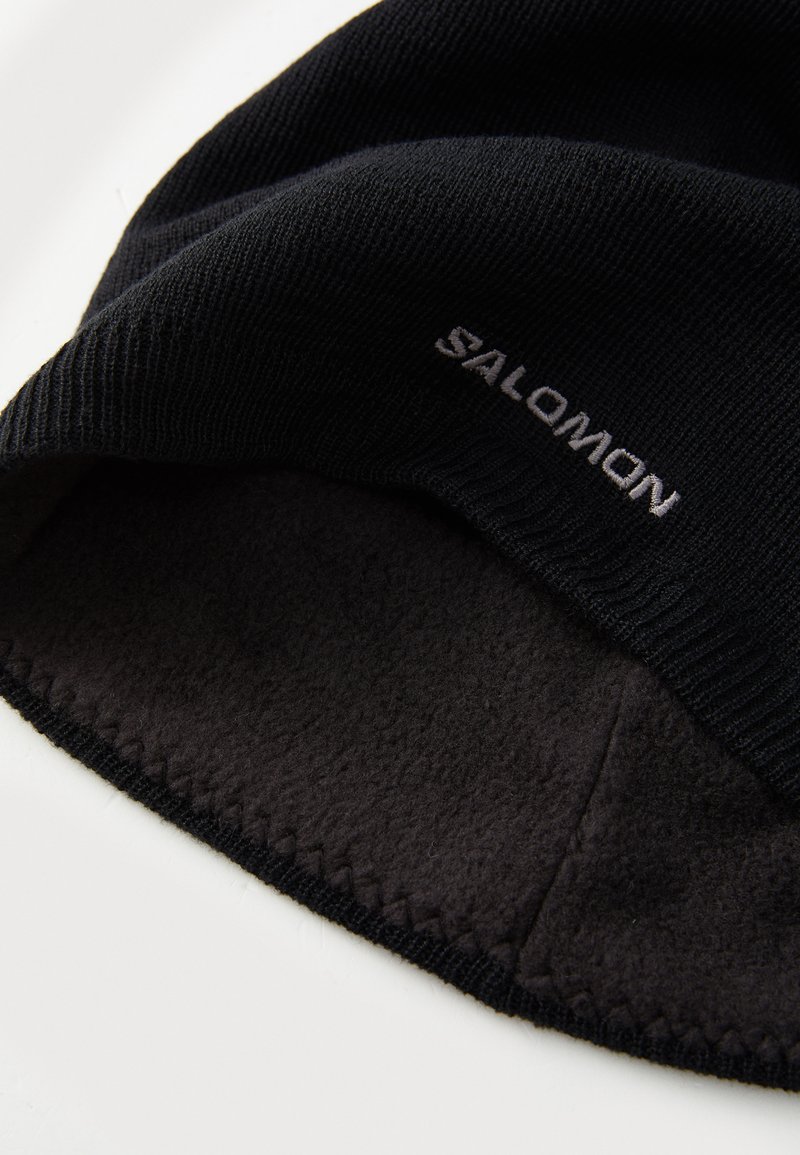 Svart mössa med ribbat stickat mönster, försedd med ett mjukt svart fleecefoder. "SALOMON"-logotypen broderad i vitt fram.