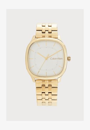 Reloj de pulsera de metal en tono dorado con esfera blanca cuadrada, índices horarios dorados minimalistas, tres agujas y logo de Calvin Klein en la esfera.