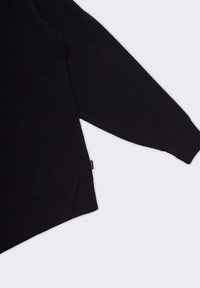 Maglione nero in maglia con texture a coste, maniche lunghe e etichetta laterale. Presenta una vestibilità comoda e un taglio dritto all'orlo inferiore.
