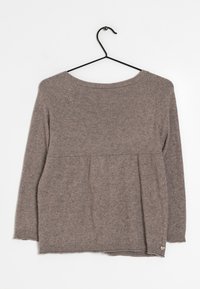 Brun långärmad stickad tröja med rund halsringning hänger på en svart metallgalge mot en vit bakgrund.