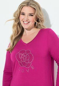 Top a maniche lunghe fucsia con scollatura a V e design di fiori in strass, con la parola "LOVE" in argento sotto il motivo floreale.