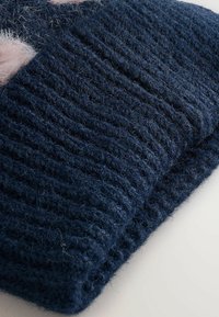 Dark blue, ribbed knit folded scarf with soft pink fuzzy accents on a light surface.
