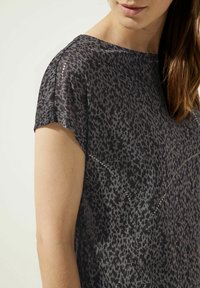 Hedvábný top s květinovým vzorem a krátkým rukávem v tmavě šedé a černé barvě, s jemnou, lehkou tkaninou a decentními ozdobami podél švů.