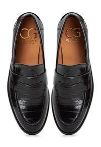 Schwarze Lackleder Slipper mit strukturierter Oberfläche, abgerundeter Zehenpartie, dekorativem Riemen und goldenem Logo auf der Innensohle.