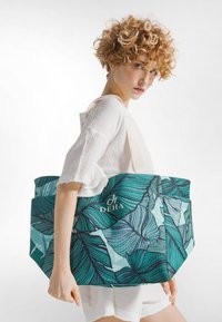 Velká taška přes rameno s výrazným vzorem listů v tyrkysové a zelené barvě, vyrobená z látky s pevnou strukturou a růžovými ramenními popruhy.