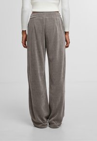 Grijze velours wijde broek met een gestructureerd oppervlak, elastische tailleband en subtiele plooien, weergegeven van de achterkant. Losse fit en zachte stof.