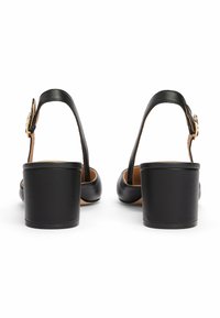 Chaussures slingback en cuir noir avec un large talon bloc, dotées d'une sangle réglable avec une boucle en ton doré et un intérieur lisse.