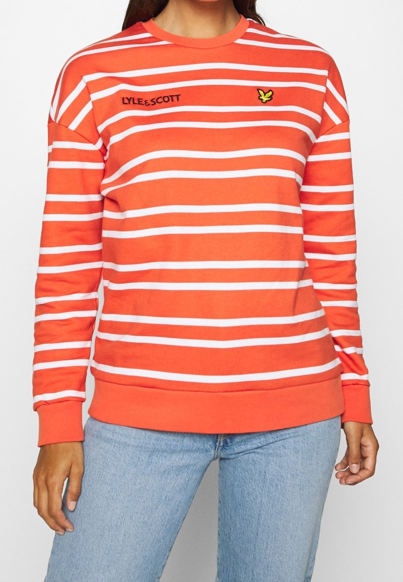 Sudadera roja con rayas horizontales blancas, cuello redondo y puños de canalé. Presenta un logo de marca bordado y un acento de mariposa.