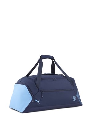Sac de voyage bleu et marine avec deux poignées de transport, compartiment principal zippé, poche avant et logo Puma. Fabriqué en tissu durable.