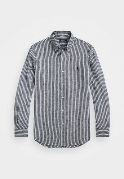 Prazna srajca s črtami v mornarsko modri in beli barvi, z ovratnikom, dolgimi rokavi in ravnim robom. Gladka tkanina z subtilno teksturo.