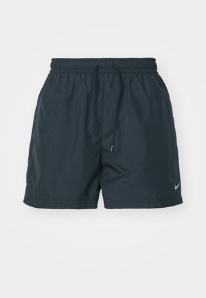 Pantaloni corti blu navy con vita elastica, cordino e tasche laterali con fessura. Presentano il logo Nike in bianco sulla parte inferiore della gamba sinistra. Materiale leggero.