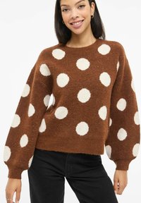 Suéter marrón de punto con grandes lunares blancos. Presenta un escote redondo y mangas abullonadas. Textura suave con un ajuste holgado.
