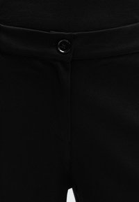 Black pants with a smooth texture, featuring a button closure, waistband, and subtle stitching details. No visible pockets.