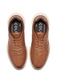 Bruna lädersneakers med en texturerad yta, rund tå, snördesign och kontrasterande beige sula. "COL"-logotyp synlig på innersulorna.