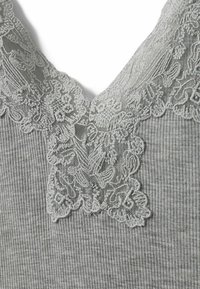 Szara prążkowana tkanina z dekoltem w kształcie litery V, ozdobiona misternym jasnoszarym koronkowym wykończeniem wzdłuż brzegów z kwiatowymi wzorami.