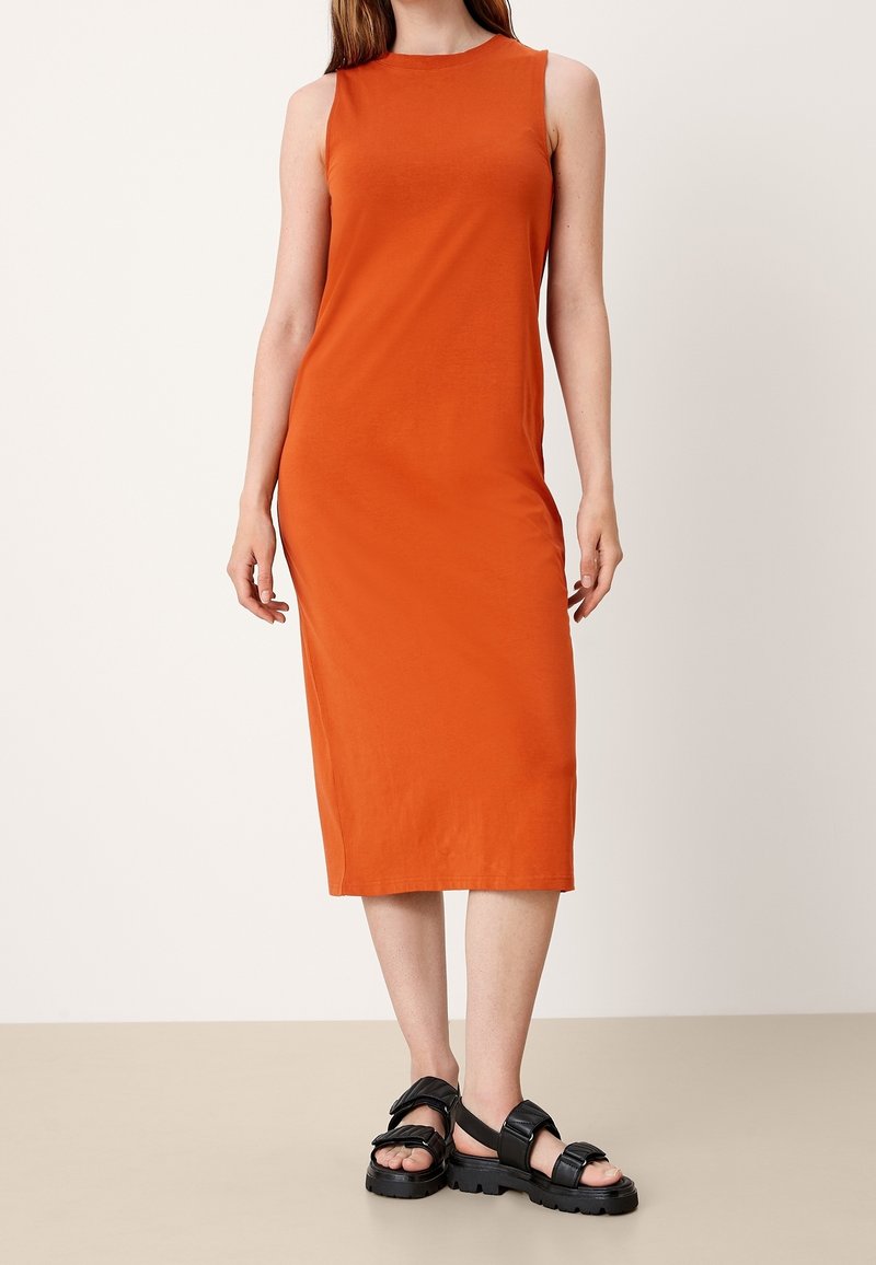Czerwona, bawełniana sukienka bez rękawów, do kolan, o dopasowanym kroju. W połączeniu z czarnymi, grubymi sandałami z regulowanymi paskami.