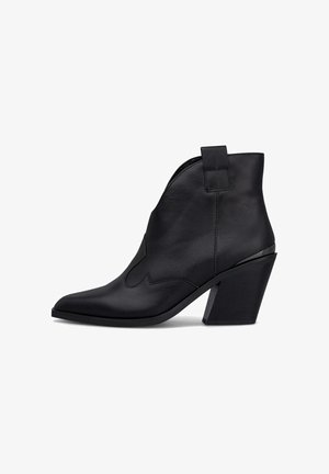 Schwarze Lederstiefelette mit spitzer Zehenform, kantigen Ausschnitten und blockiertem Absatz. Glatte Textur mit Nähdetails und seitlicher Zuglasche.