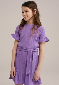 Violet medvilnės suknelė su trumpomis volanų rankovėmis, tekstūruotu raštu ir juosmenyje surišta juosta. Skeltukas turi volanų apdailą.