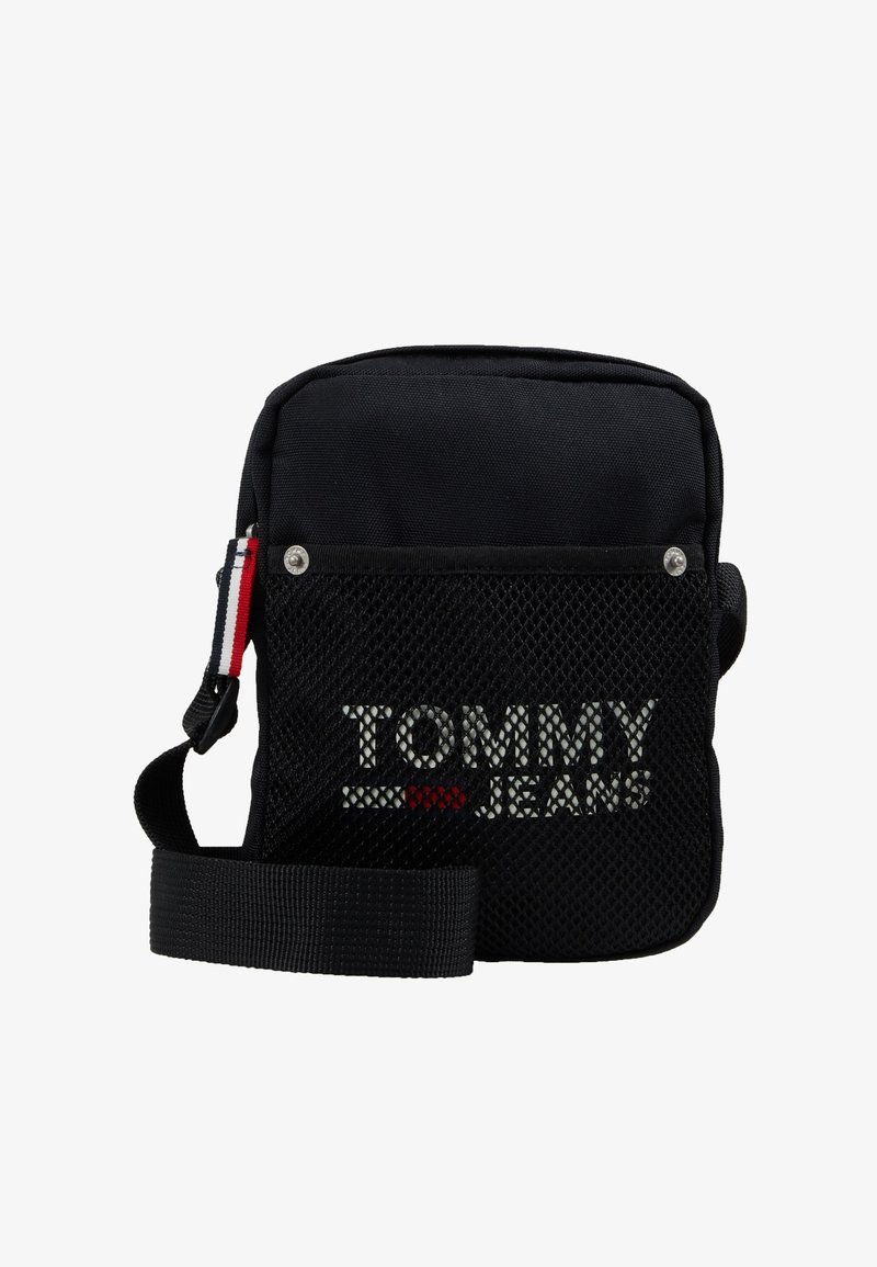 Borsa a tracolla nera in tessuto con frontale in rete. Presenta un logo bianco e rosso, una tracolla regolabile e dettagli con bottone a pressione.