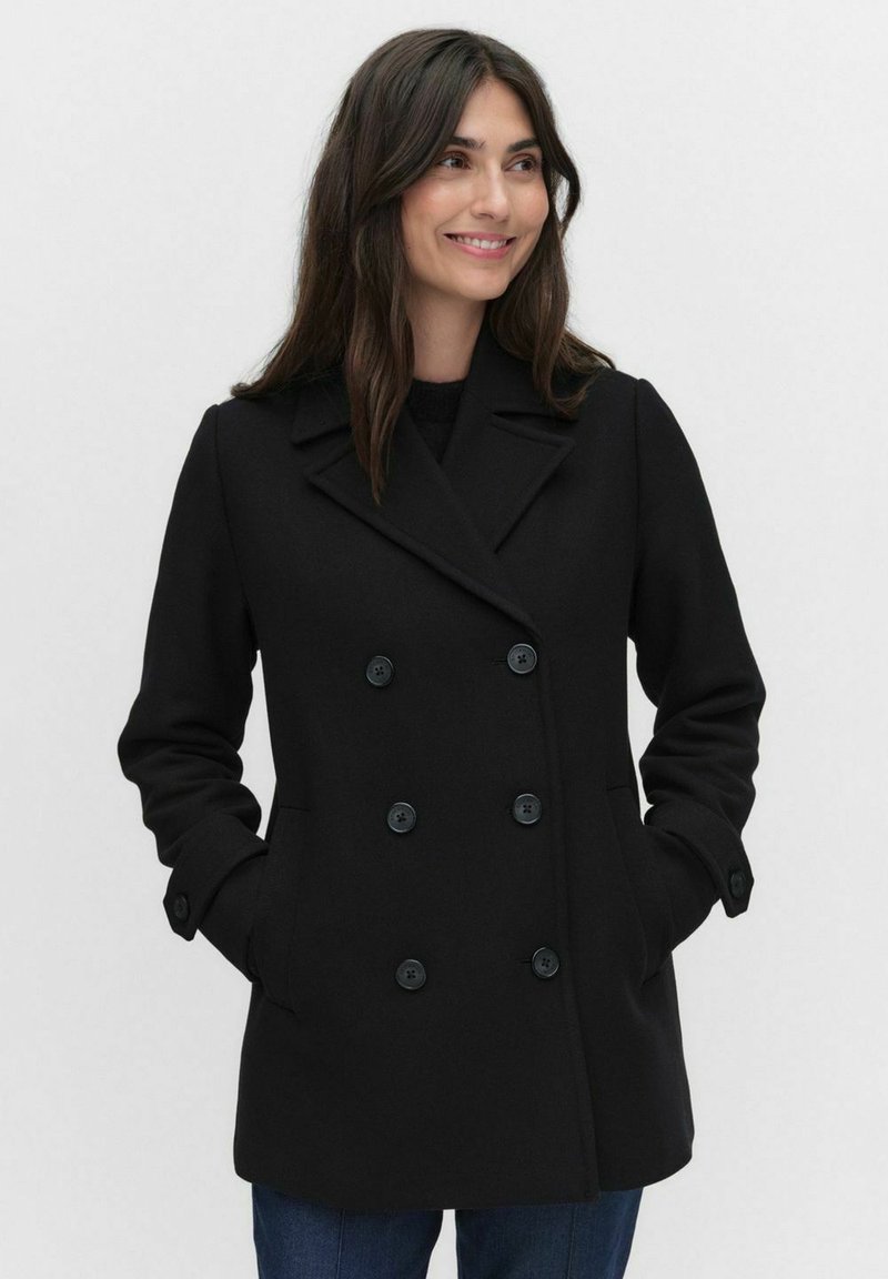 Mustan kaksirivisen villakangas takin, jossa on suuret mustat napit, terävä kaulus ja sivutaskut. Tasainen tekstuuri ja muotonsa mukaisesti istuva malli.