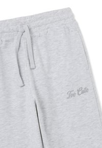 Graue, cropped Sweatpants mit elastischem Bund, ausgestattet mit einem Kordelzug und dem Text "Too Cute" in Hellgrau auf der rechten Seite.