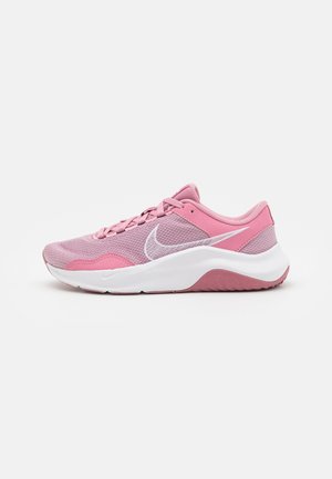 Chaussure de course Nike rose et violet clair avec logo swoosh blanc et semelle blanche épaisse, vue de côté sur un fond uni.