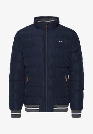 Sötétkék bélelt kabát magas gallérral, elülső cipzárral, szürke csíkos mandzsettákkal és narancssárga cipzár részletekkel. A mellkas területén egy apró logó található.