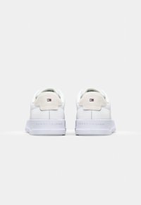 Baskets blanches avec une tige en cuir lisse, des accents en daim doux, et une languette de talon marquée d'un logo. Semelle en caoutchouc et design minimaliste.