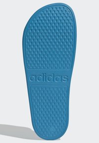 Blauwe rubberen sandaalzool met een gestructureerd diamantpatroon en een reliëflogo. Ronde teen en lichte ondersteuning van de voetboog.